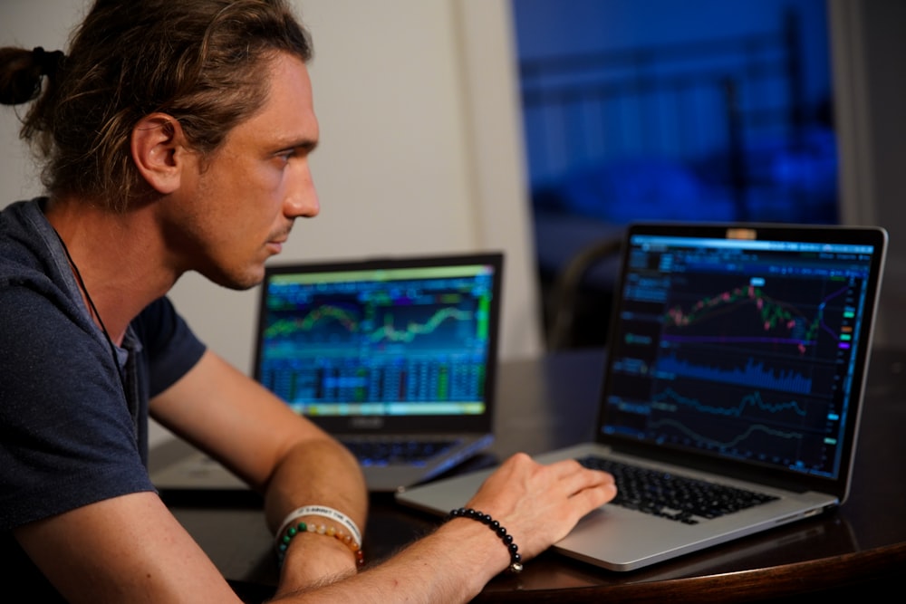 Man concentrating on multiple cryptocurrency market graphs on laptop screens